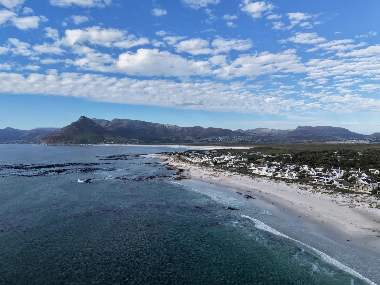 Weite Küstenlinie von Kommetjie mit Bergen im Hintergrund